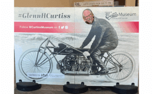 Paul Fromm's face, in a cutout of the Glenn Curtiss museum motorcycle