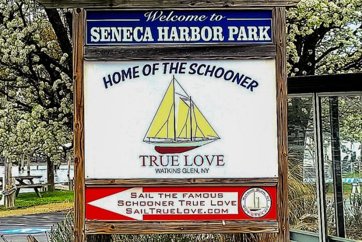 An outdoor sign for a harbor park, advertising a sailing company that offers tours