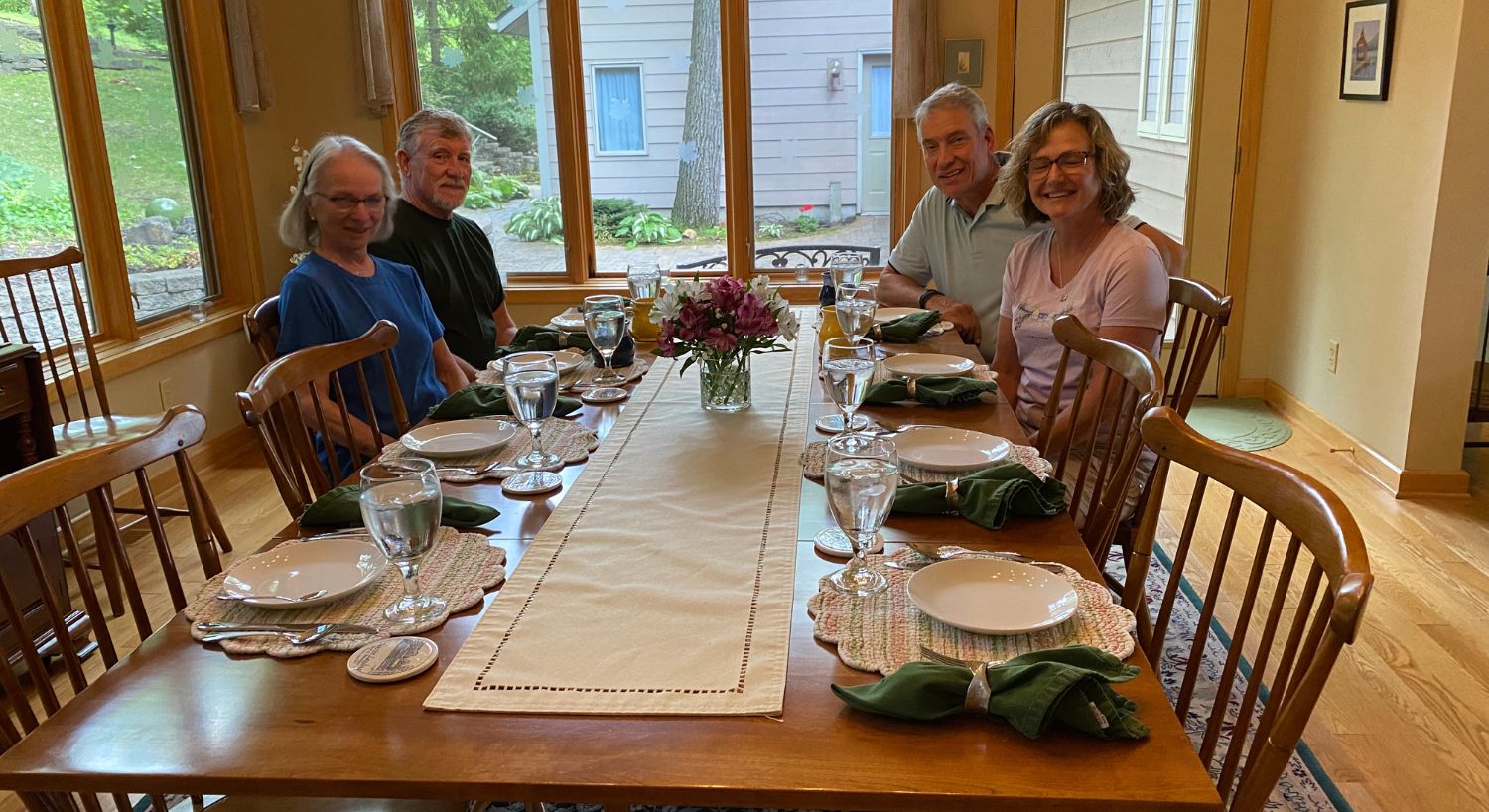 Two couples sitting at a breakfast table in a dining room with walls of windows