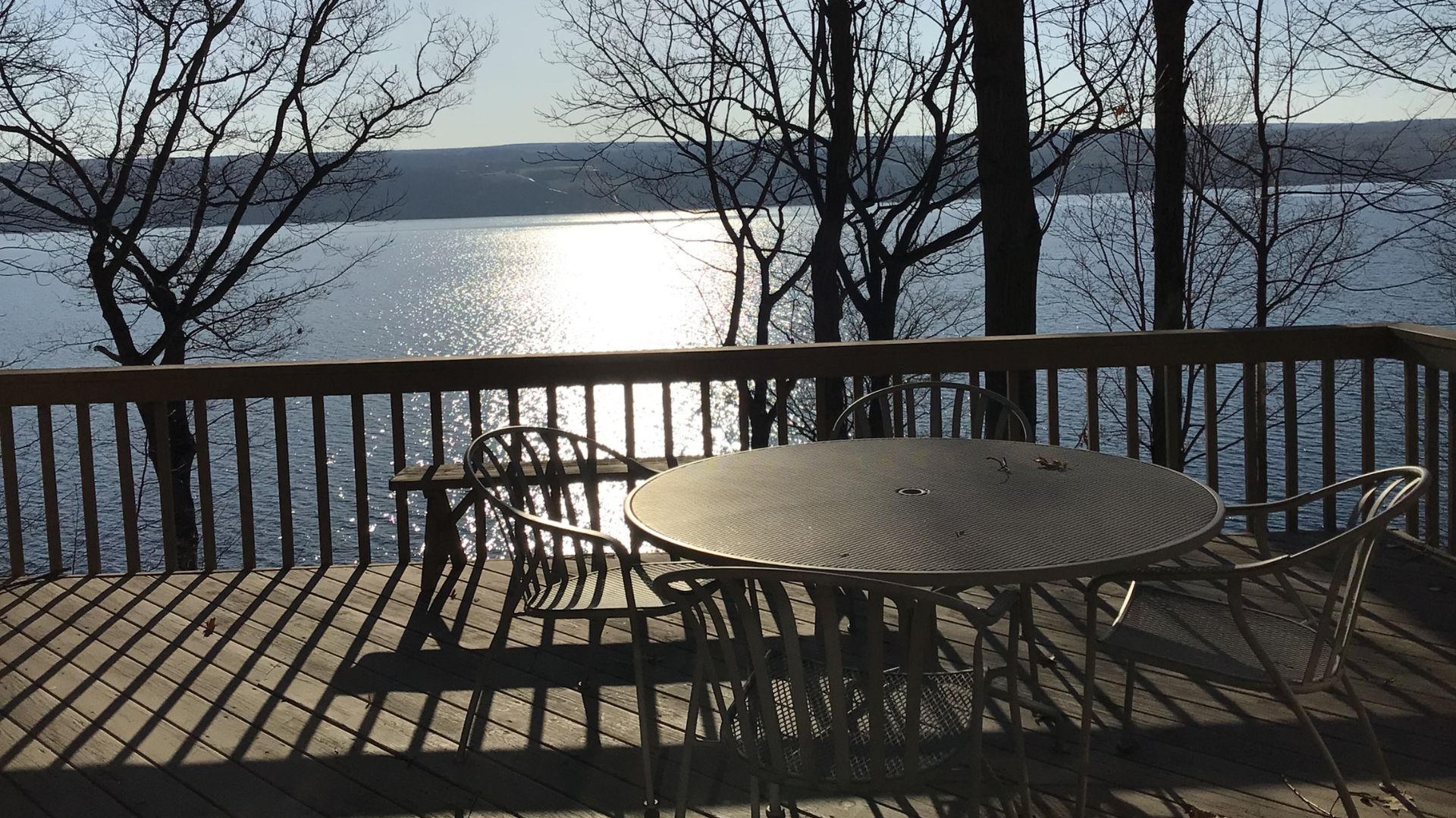 Outdoor deck with round patio table and chairs overlooking an expansive lake