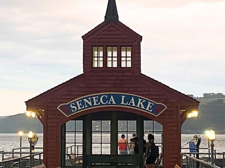 A red building at the end of a pier with lanterns overlooking a large lake